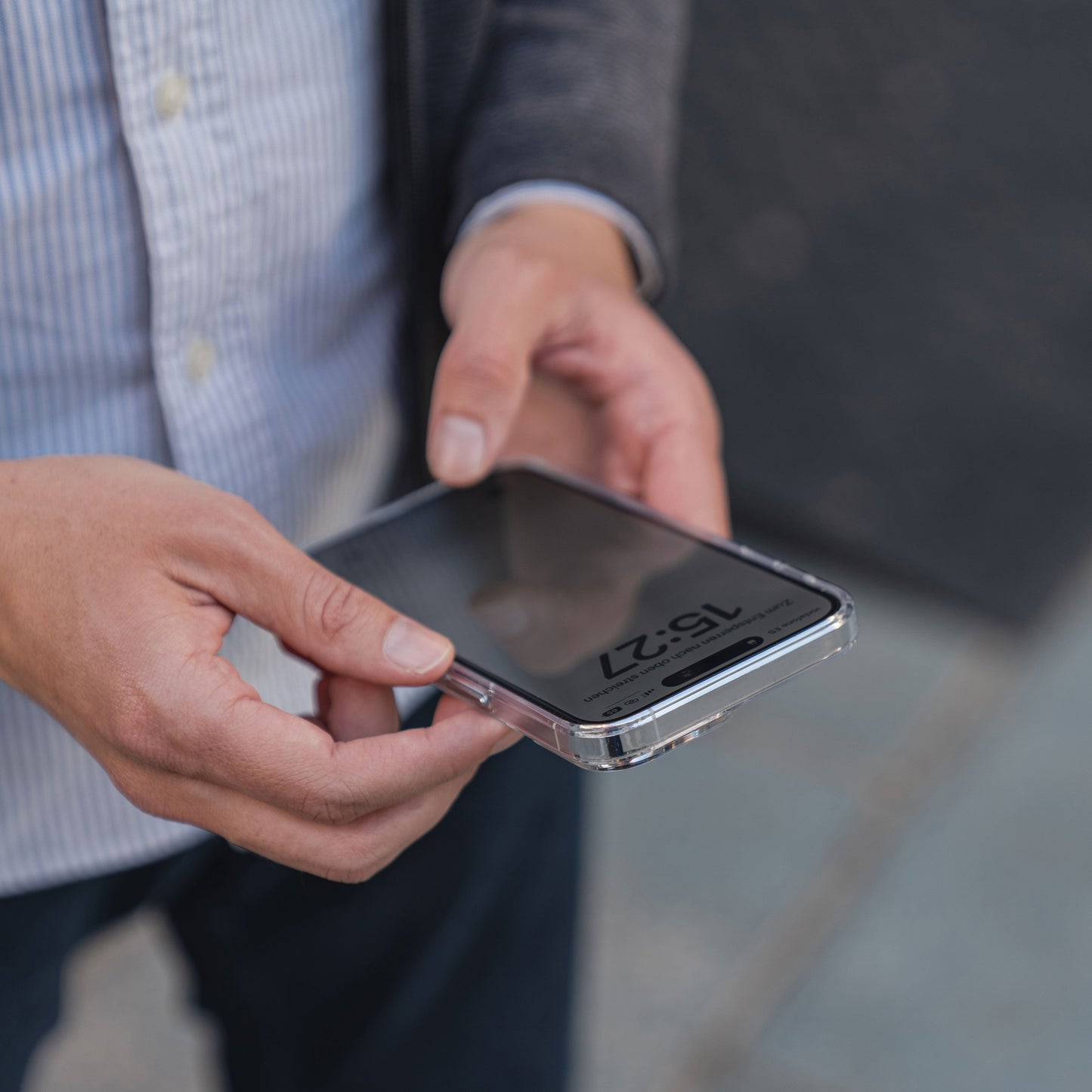 Eine Person hält ein Smartphone mit der Anzeige 15:27, geschützt durch das MR PROTECT iPhone 15 Pro Max CLEAR Case aus kratzfestem Polycarbonat – idealer Schutz von MR PROTECT.
