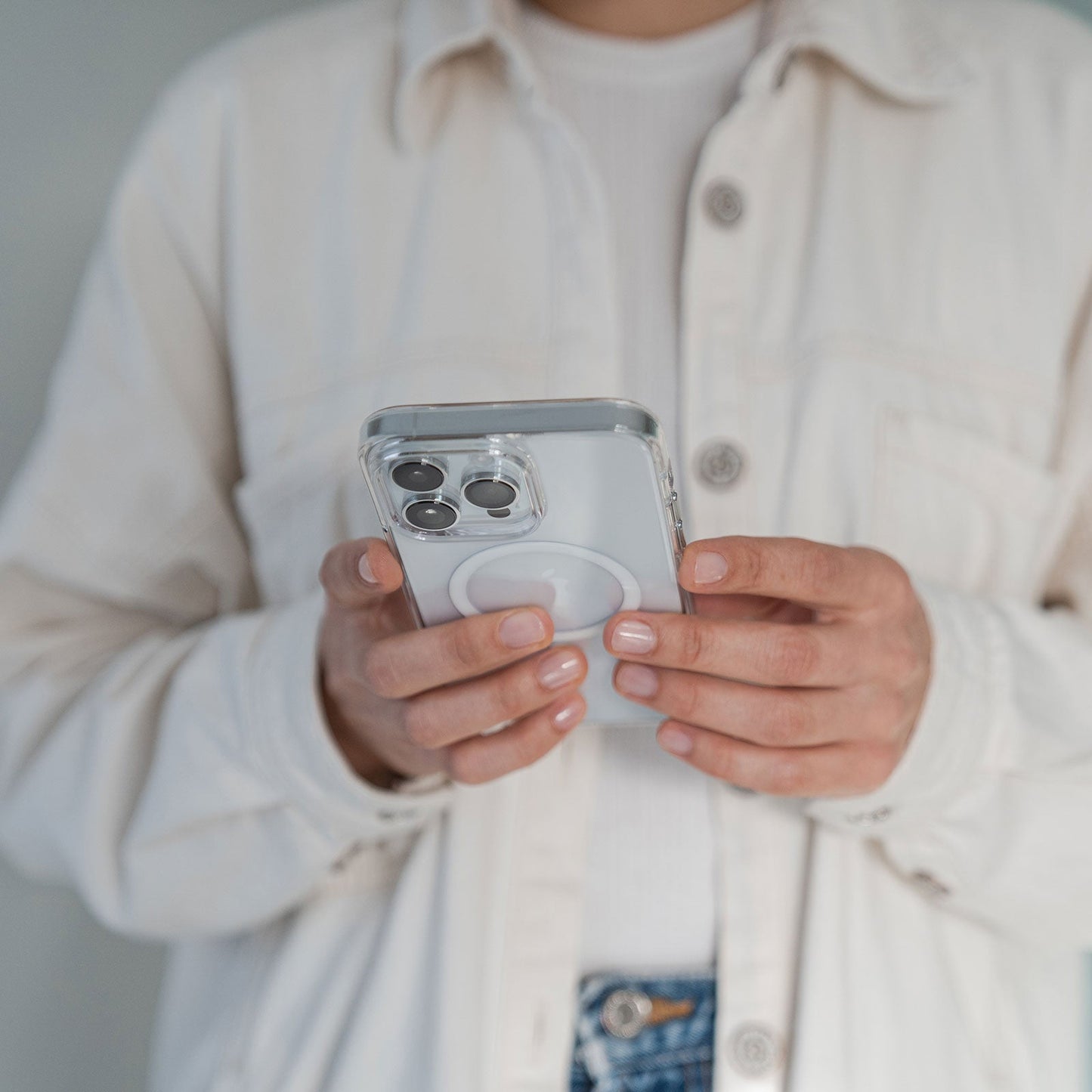 Person in cremefarbener Jacke hält ein iPhone 17 mit dem arktis iPhone Air Clear Case mit MagSafe und blickt auf den Bildschirm.