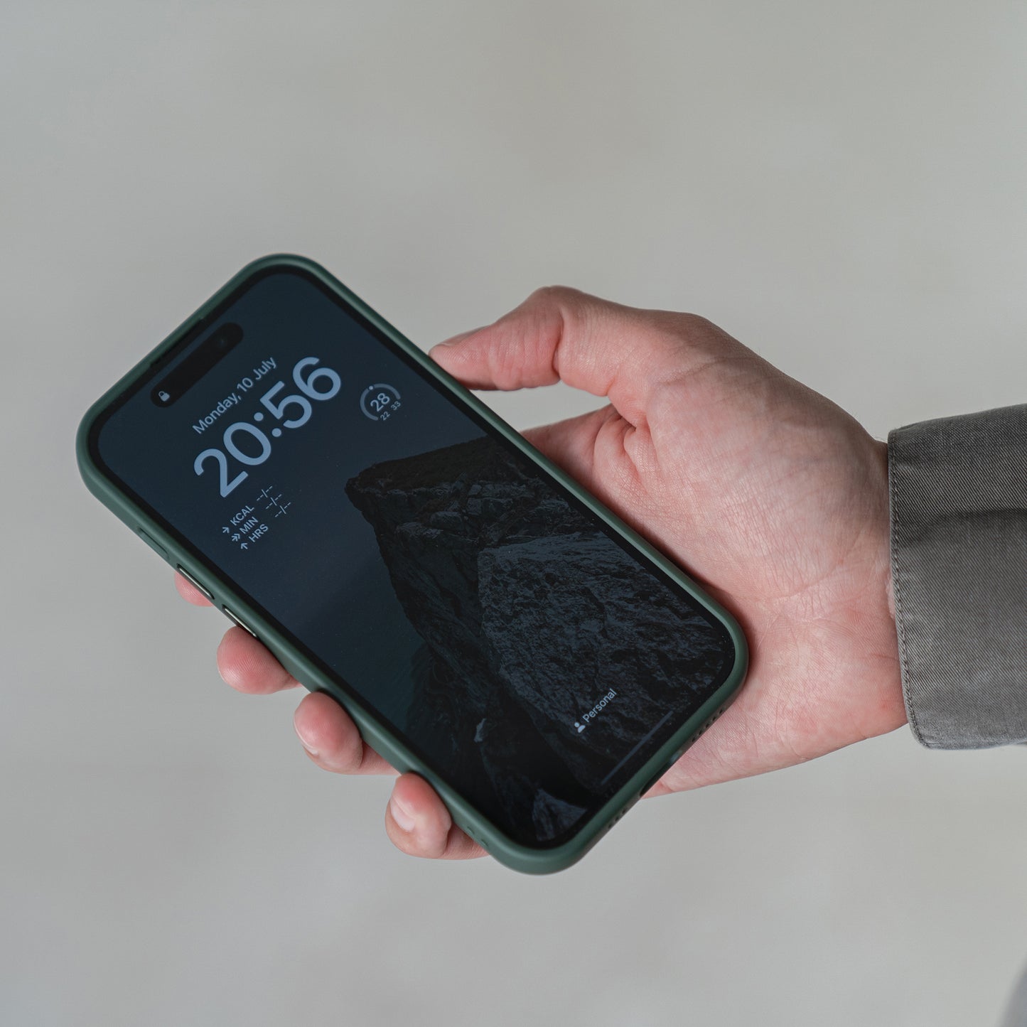 Eine Person in einer grauen Hülle hält ein iPhone 15 mit dem MR PROTECT iPhone 15 Case Matt. Die minimalistische Hülle bietet Stoßdämpfung. Der dunkle Sperrbildschirm des Telefons zeigt 20:56 Uhr, Montag, 10. Juli, Wetterinformationen und ein Bergbild.
