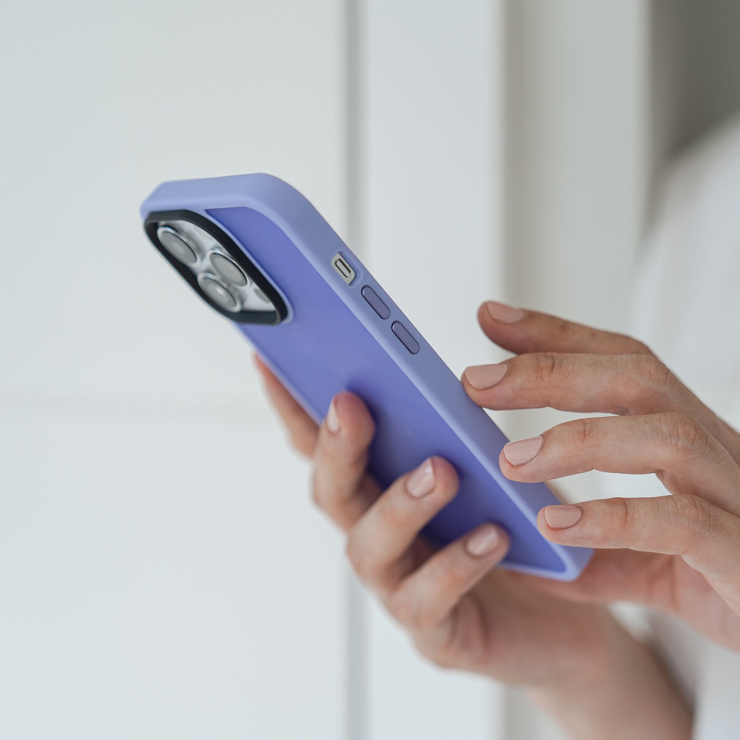 Eine Person hält ihr Smartphone in einer violetten MR PROTECT iPhone 15 Hülle Matt, die aus einem stoßabsorbierenden TPU-Silikon-Material und minimalistischer, matter Optik besteht, während sie den Bildschirm vor einem sanft beleuchteten, schlichten Hintergrund berührt.