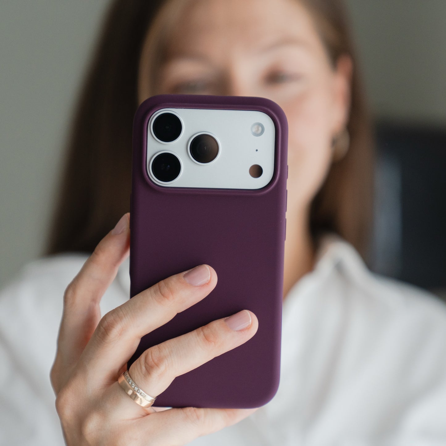 Person mit einer Arktis iPhone 18 Pro Max-Silikonhülle in Burgunderrot mit MagSafe; die Kameralinsen sind zu sehen, das Gesicht ist unscharf.