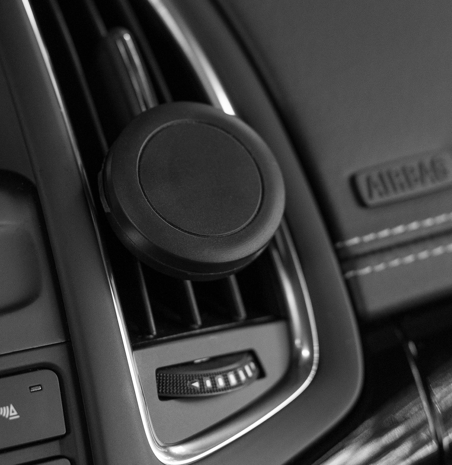 Nahaufnahme einer Autolüftungsöffnung mit einer daran befestigten runden magnetischen Telefonhalterung.