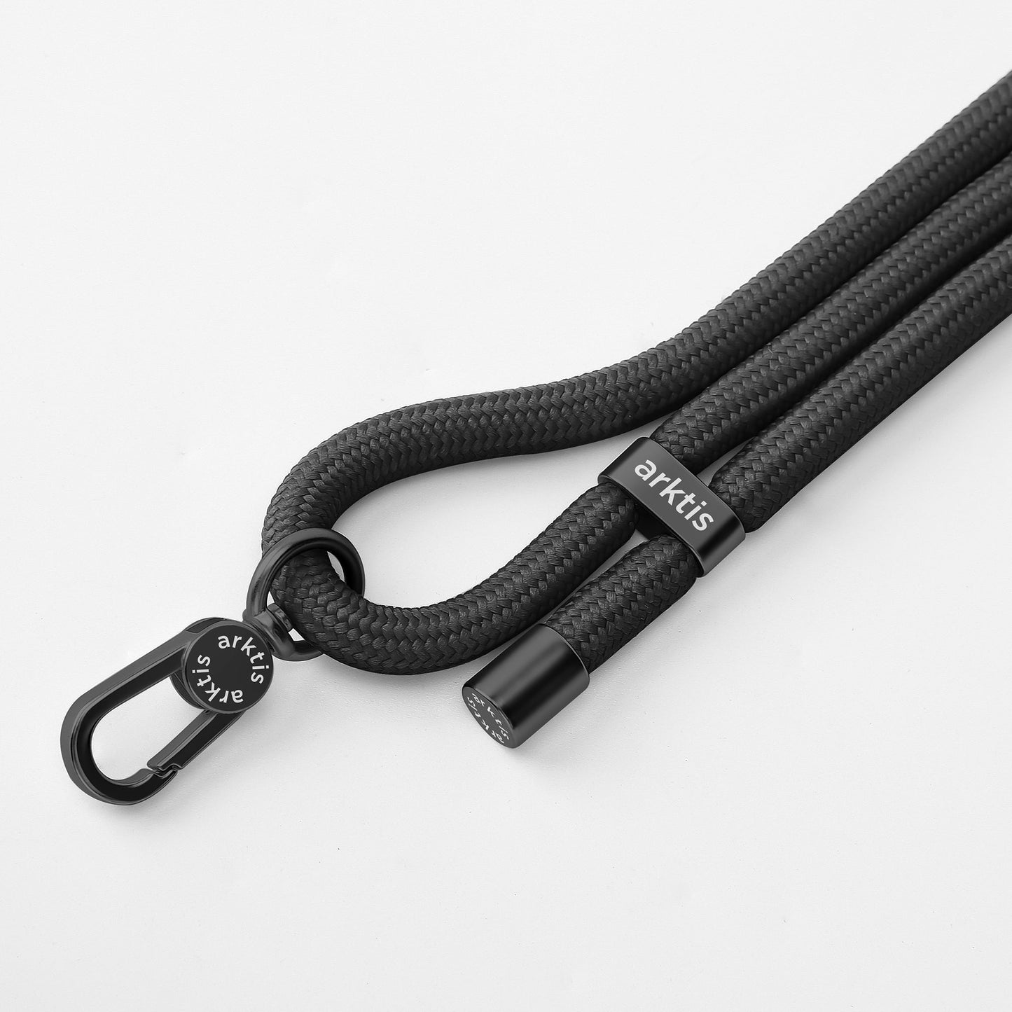 Die Arktis Lanyard Handykette fürs Handgelenk ist ein schwarzes, geflochtenes Armband mit Metallverschluss, verstellbarer Länge und Arktis-Logo. Dieses stilvolle Smartphone-Accessoire präsentiert sich vor einem sauberen weißen Hintergrund.