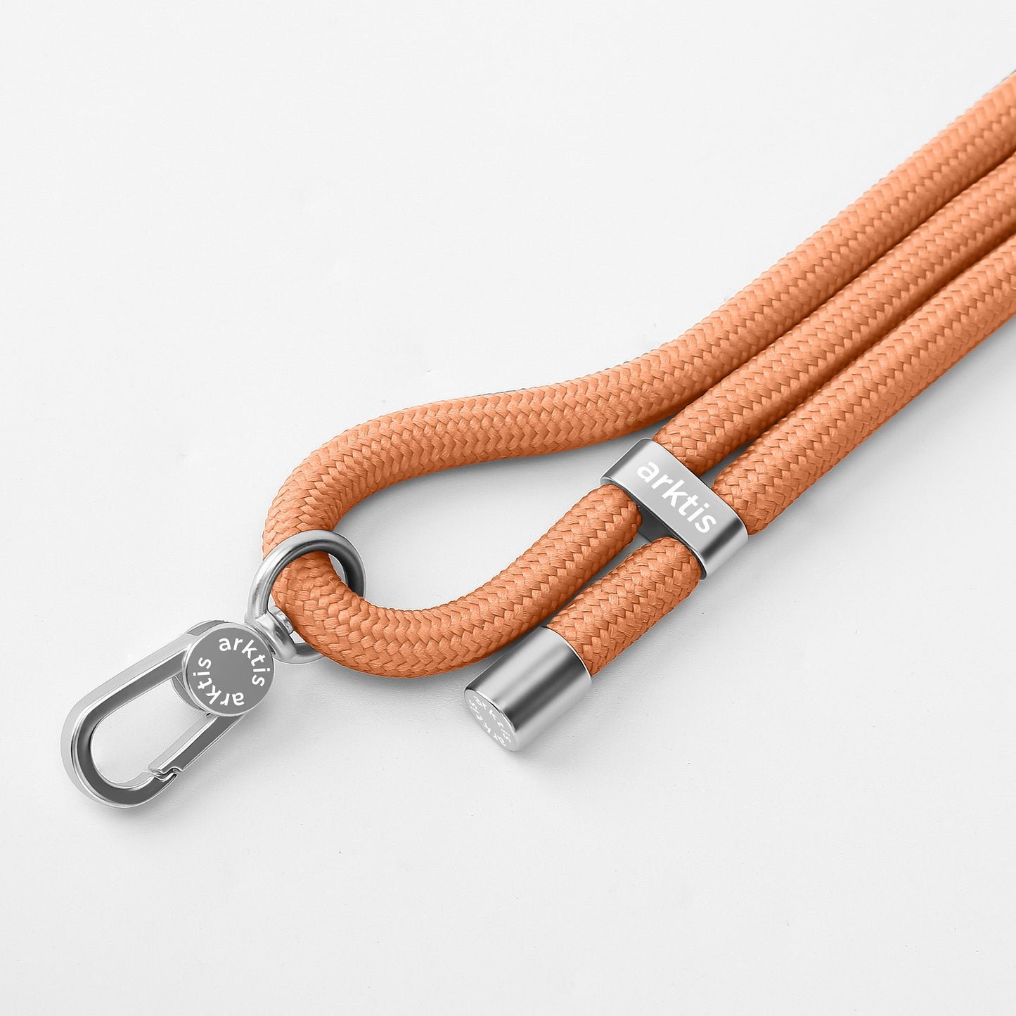 Die Arktis Lanyard Handykette fürs Handgelenk von Arktis verfügt über ein orangefarbenes geflochtenes Seil mit silbernem Clip und Metallakzenten – ein ideales Mode-Accessoire oder Smartphone-Zubehör, dargestellt auf weißem Hintergrund.