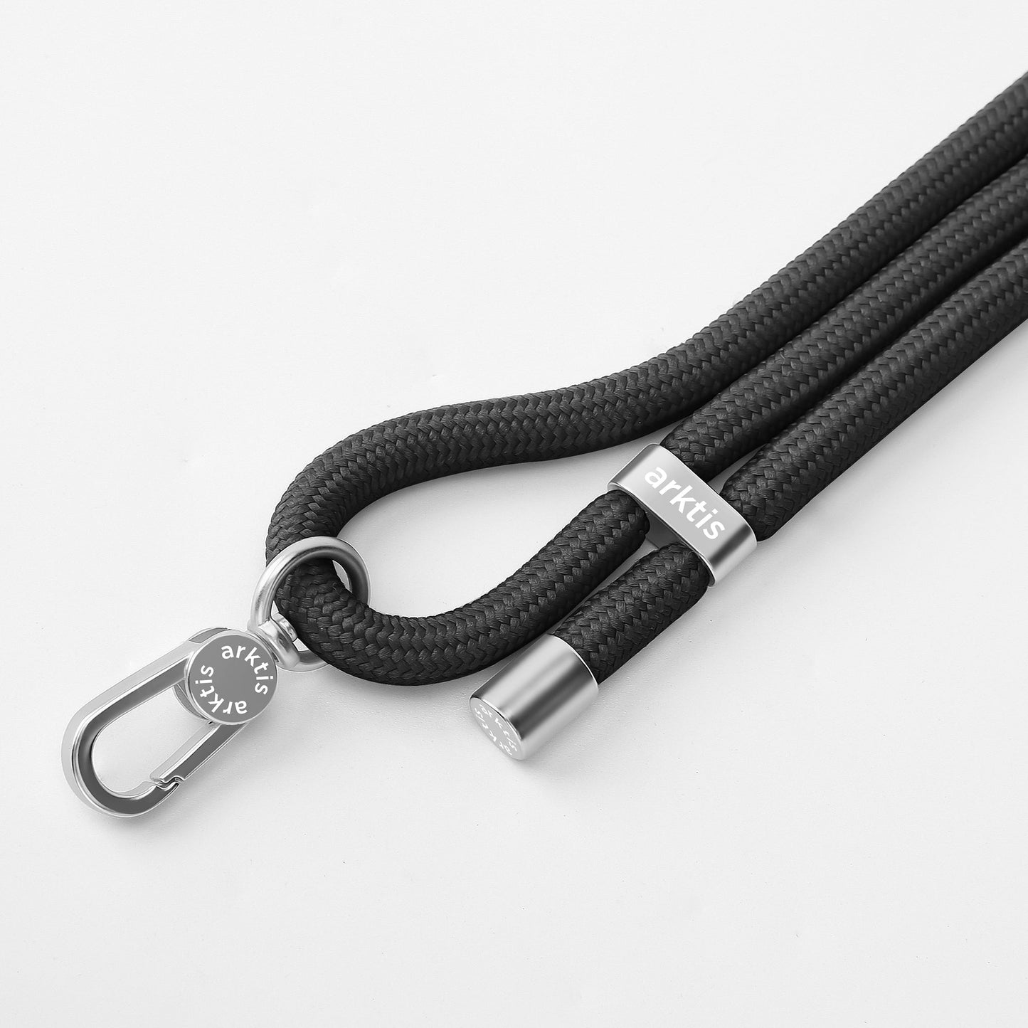Die arktis Lanyard Handykette fürs Handgelenk von Arktis verfügt über ein schwarzes geflochtenes Design mit Metallclip und silbernen Akzenten – perfekt als Smartphone-Zubehör und trendiges Mode-Accessoire, abgebildet auf weißem Hintergrund.