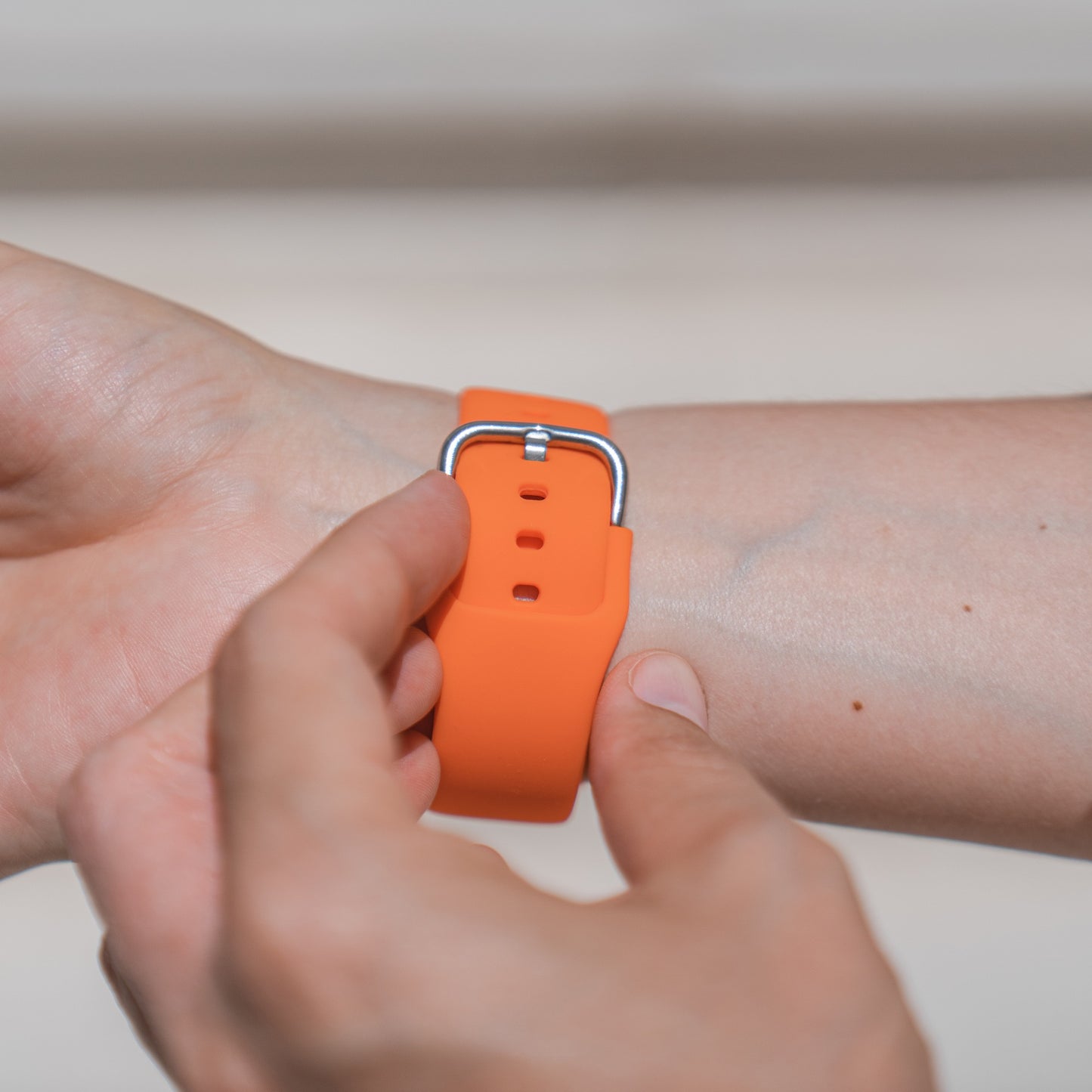 Eine Person befestigt ein Arktisband Apple Watch Silikonarmband „Aqua“ an ihrem Handgelenk und zeigt damit ein sportliches Band, das mit der Apple Watch kompatibel ist.