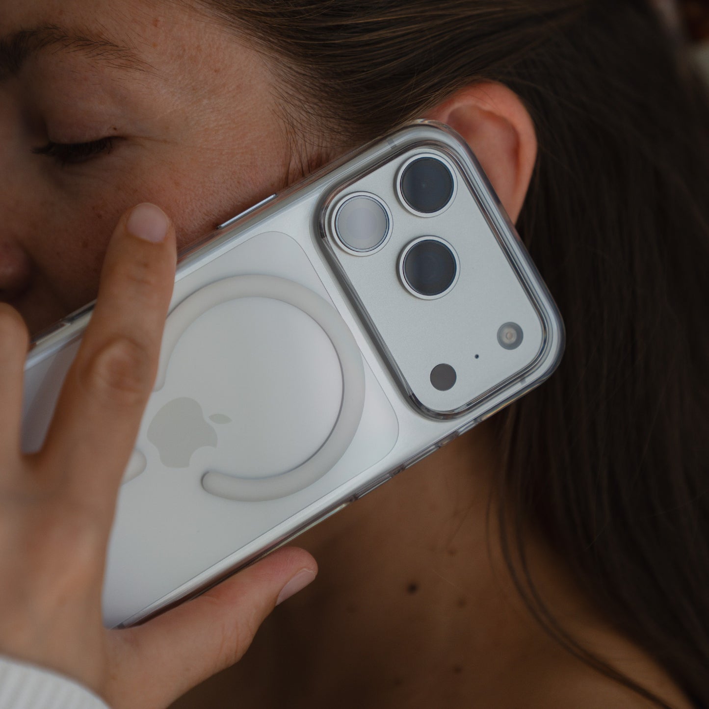 Eine Person hält ein arktis iPhone 17 Pro Max PureCase mit MagSafe nahe an ihr Gesicht, das die Kamera des Telefons und das Apple-Logo zeigt. Diese transparente, stoßfeste Hülle von arktis bietet stilvollen Schutz und volle MagSafe-Kompatibilität.
