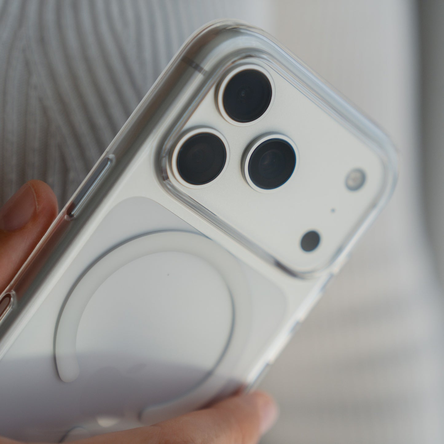 Eine Hand hält ein iPhone 17 Pro Max im arktis iPhone 17 Pro Max PureCase mit MagSafe, einer transparenten, stoßfesten Hülle von arktis mit drei rückseitigen Kameras und einem MagSafe kompatibler Ring.