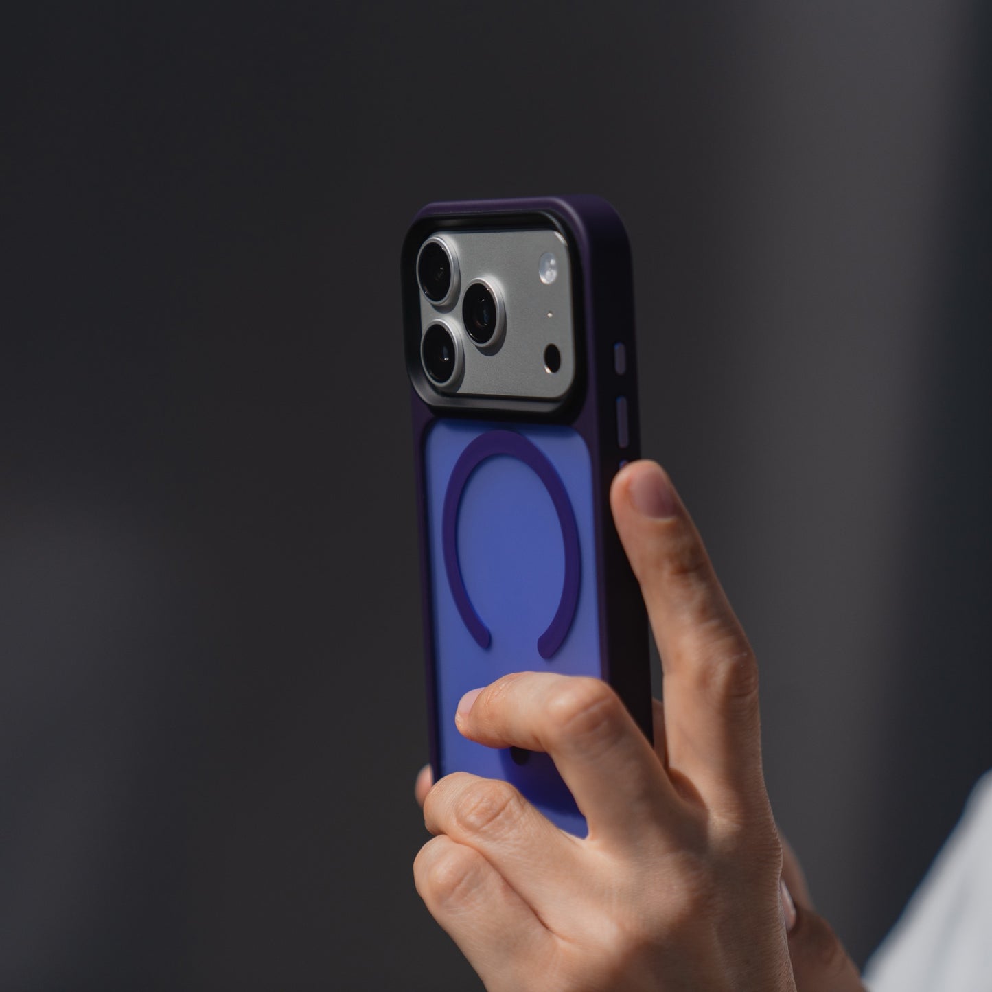Eine Hand hält die Arktis arktis iPhone 17 Pro Solid Case mit MagSafe, eine blaue matte Schutzhülle von Arktis, MagSafe kompatibel, abgebildet vor einem dunklen Hintergrund.