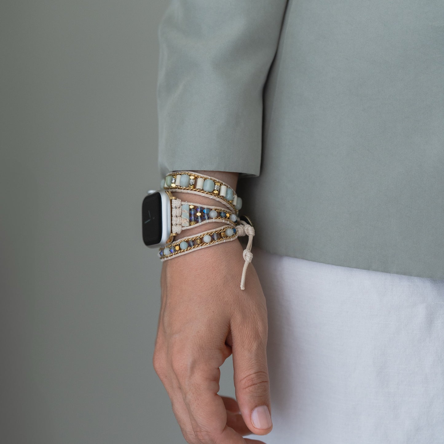 Jemand trägt das arktisband Apple Watch Armband "Dream Catcher" von arktisband, gepaart mit Perlenarmbändern und einer hellgrauen Jacke.