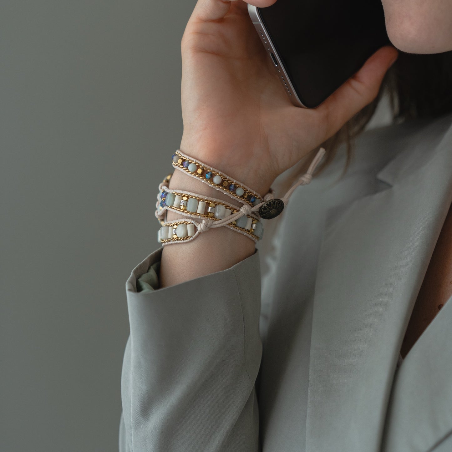 Eine Person in einem grauen Blazer hält sich ein Telefon ans Ohr und trägt das arktisband Apple Watch Armband "Dream Catcher" von arktisband am Handgelenk.
