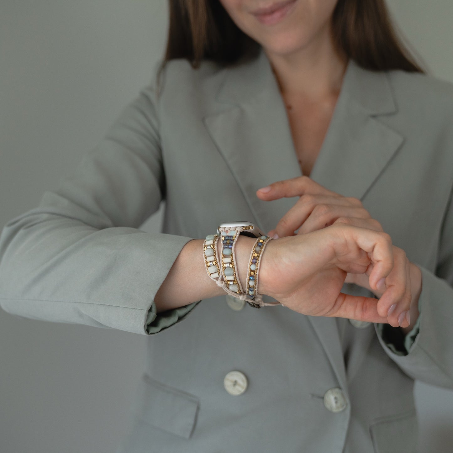Eine Frau in einem hellgrauen Blazer trägt das stylische arktisband Apple Watch Armband "Dream Catcher" mit einem eleganten Edelstahladapter am Handgelenk.