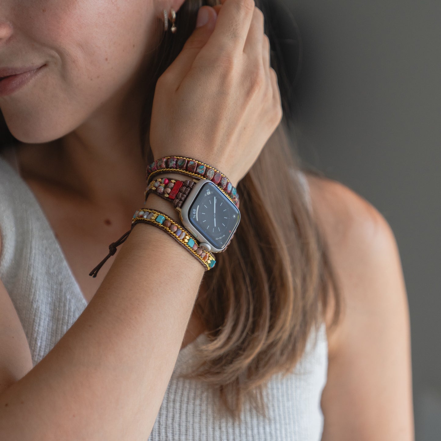 Eine Frau trägt das arktisband Apple Watch Armband "Dream Catcher" mit einem Edelstahladapter, gestylt mit bunten Boho-Armbändern, vor einem neutralen Hintergrund.