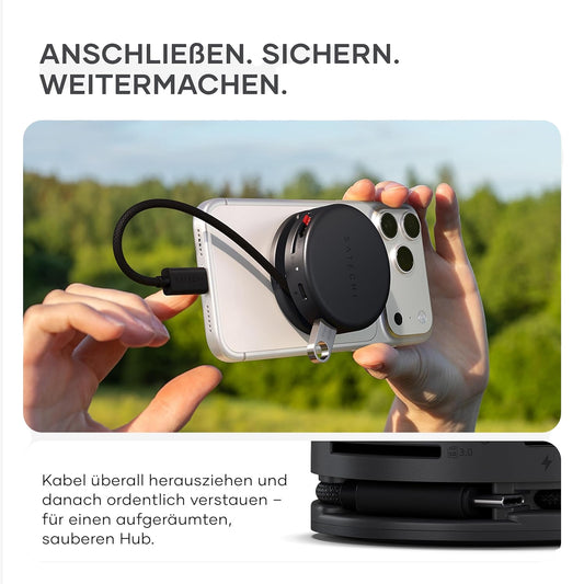 Jemand bringt einen Satechi Kabel-Organizer und seinen Satechi OntheGo 7-in-1 Multiport-Adapter an einem Telefon im Freien an; die Nahaufnahme zeigt den Organizer im Detail unten.