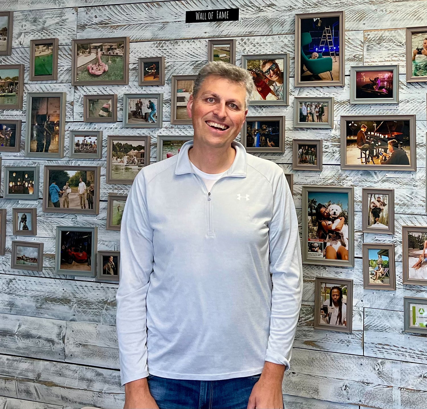Inhaber Rainer Wolf steht vor einer Bilderwand