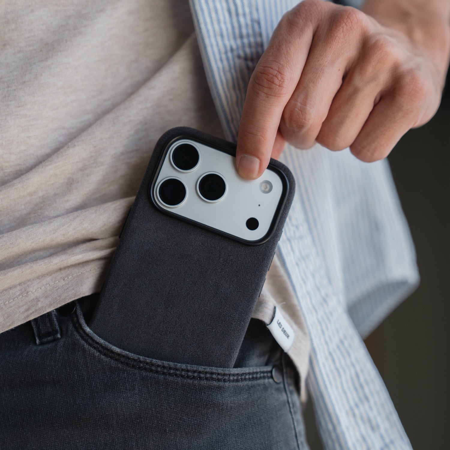 Jemand schiebt ein Smartphone mit der arktis iPhone 17 Pro Hülle aus Alcantara von arktis in die Vordertasche einer dunklen Jeans.