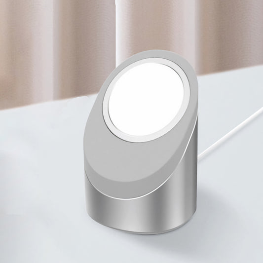 Das kabellose Ladegerät arktis MagSafe NightStand von arktis in modernem Silber steht auf einer weißen Fläche neben beigen Vorhängen.