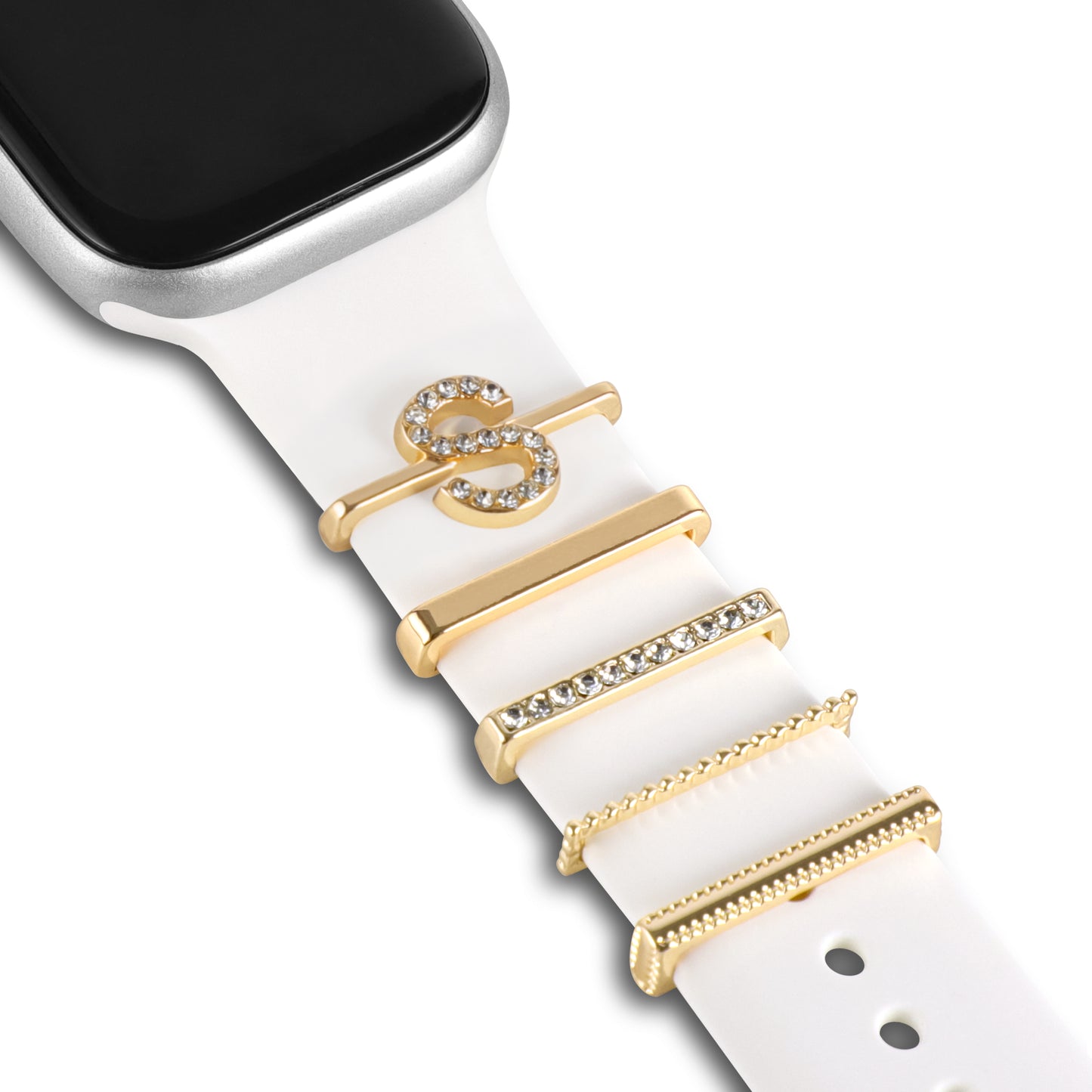 Eine Nahaufnahme eines Arktisband-Apple-Watch-Armbands mit weißem Band und fünf goldenen und strassbesetzten Arktisband-Apple-Watch-Charms im „S-Stil“ – darunter ein S-Buchstabe und Balken-Charms – perfekt, um Ihrem Look Glanz zu verleihen.