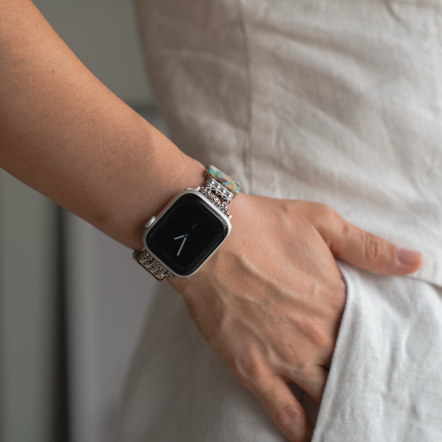 Eine Person, die das arktisband Apple Watch "Stone Loop" Armband trägt, die Hand in der Tasche eines hellen Kleidungsstücks.