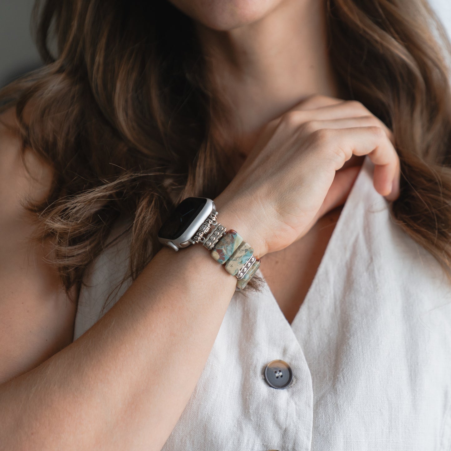 Eine Frau in einem ärmellosen Top präsentiert die arktisband Apple Watch "Stone Loop" von arktisband als elegantes Accessoire am Handgelenk.