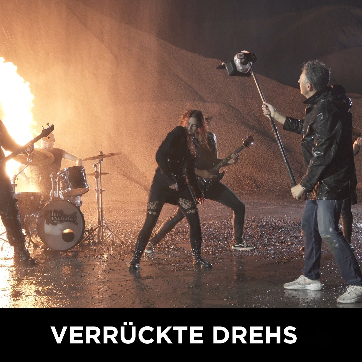 Eine Rockband spielt nachts draußen, hinter ihnen Flammen, während ein Crewmitglied mit einem Galgenmikrofon daneben steht und die wilde Energie des Filmemachens einfängt. Der Text unten lautet: Wolffilms Academy Online-Kurs – Einfach filmen lernen, von Rainer Wolf.