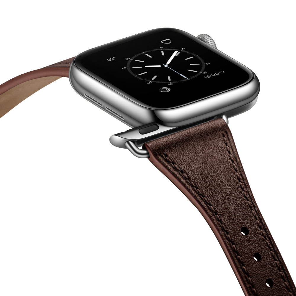 Eine Nahaufnahme eines Arktisband Apple Watch Lederarmbands „Napoli“ mit braunem Lederband und Edelstahl-Dornschließe, befestigt an einer Smartwatch mit quadratischem schwarzen Display mit analogem Zifferblatt vor weißem Hintergrund.