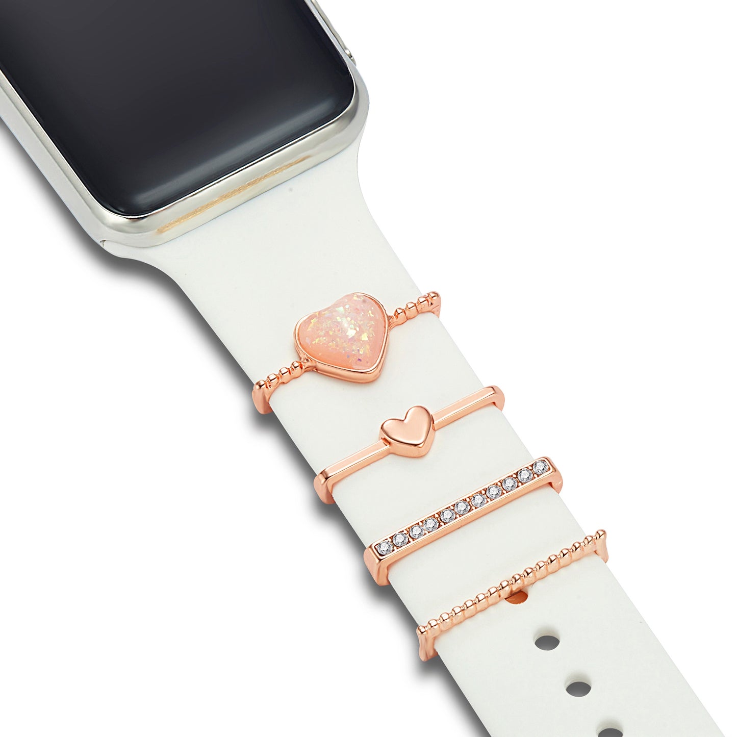 Eine Nahaufnahme der Arktisband-Apple-Watch-Armbandanhänger auf einem weißen Arktisband, die drei Anhänger aus Roségold zeigt: ein Herz mit einem rosa Stein, ein kleines massives Herz und einen Balken mit klaren Steinen – alle individuell anpassbar.