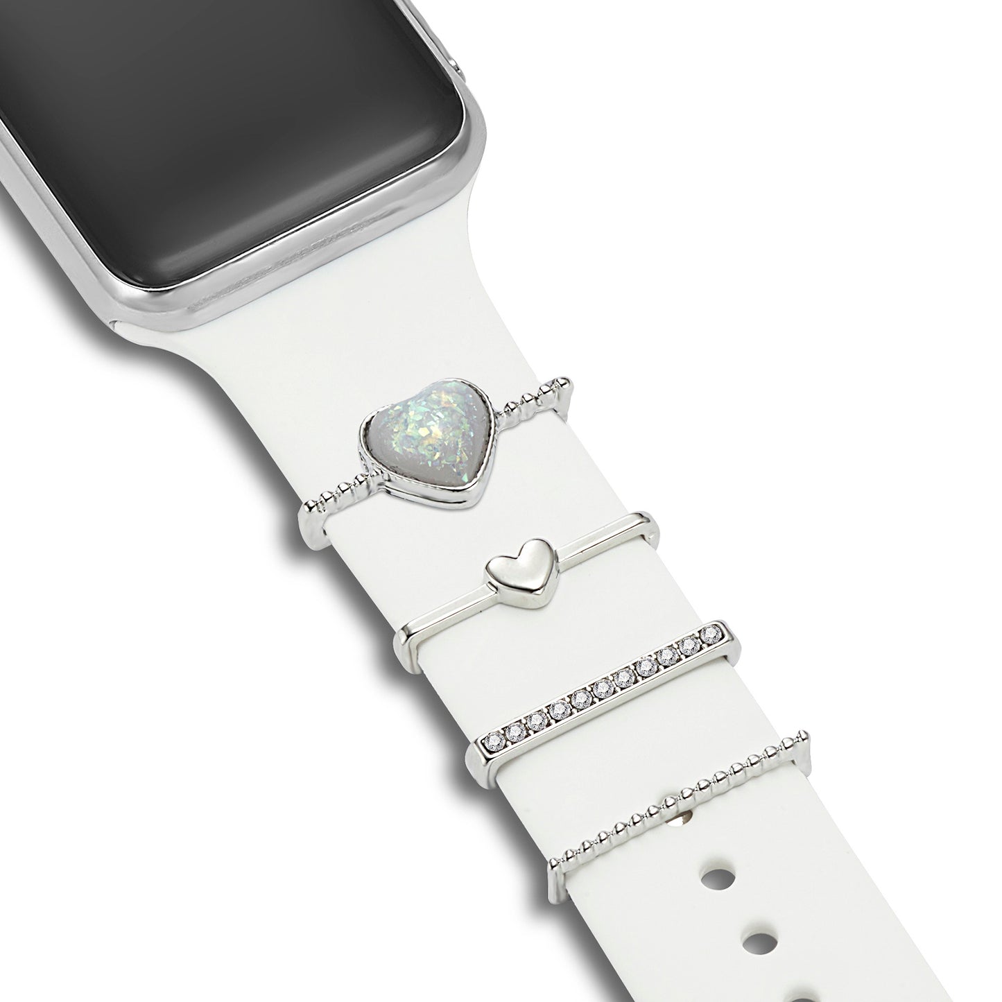 Die arktisband Apple Watch Armband Charms von arktisband bestehen aus vier silbernen Ringen – einem herzförmigen Opal, einem kleinen Herz, Kristallen und Perlen – die in einer Reihe auf einem weißen Apple Watch Band angeordnet sind.