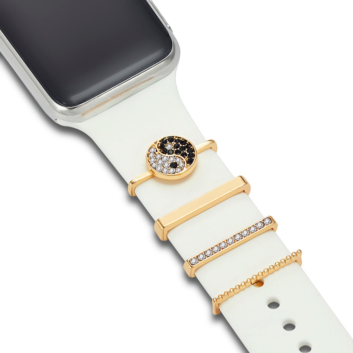 Ein weißes Apple Watch-Armband mit vier goldenen Arktisband-Anhängern: ein Yin-Yang-Symbol mit schwarzen und weißen Strasssteinen, zwei rechteckige Balken (einer schlicht, einer mit Strasssteinen) und ein goldener Anhänger mit Perlen. Kompatibel mit den Arktisband-Armband-Anhängern der Apple Watch.