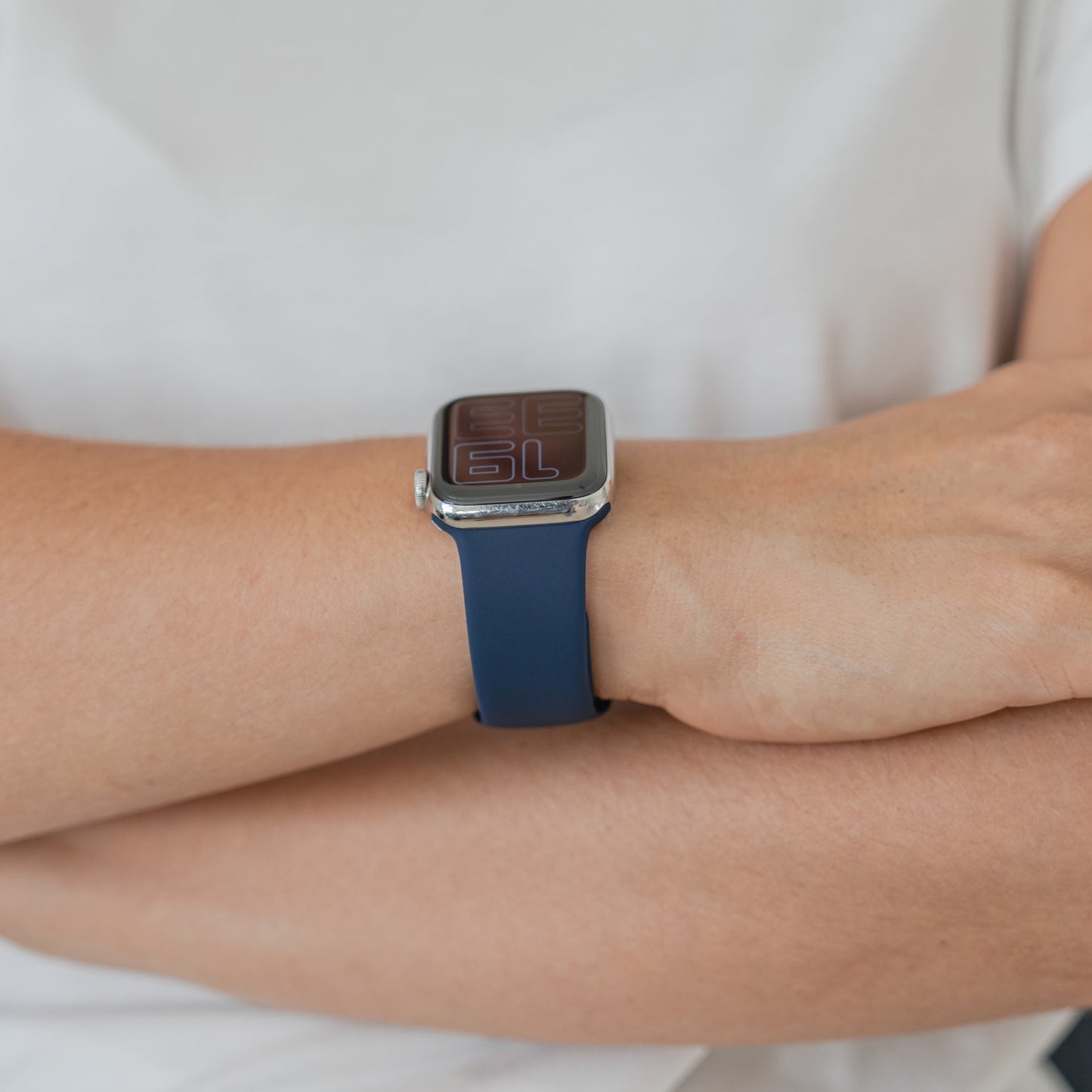 Eine Person, die das Arktisband Apple Watch Silikonarmband „Aqua“ trägt, verschränkt die Arme und trägt ein schlichtes weißes Hemd.