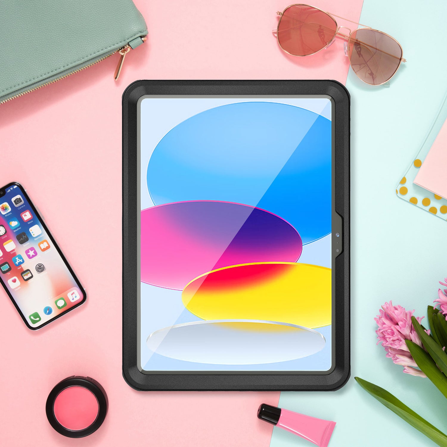 Ein iPad 11" (2022/2025) zeigt leuchtende Farben auf einem pastellfarbenen Schreibtisch mit Blumen, iPhone, Sonnenbrille und Make-up – geschützt durch das wasserdichte ArktisPRO-Case mit stoßfestem Rahmen für zusätzlichen Stil und Haltbarkeit.