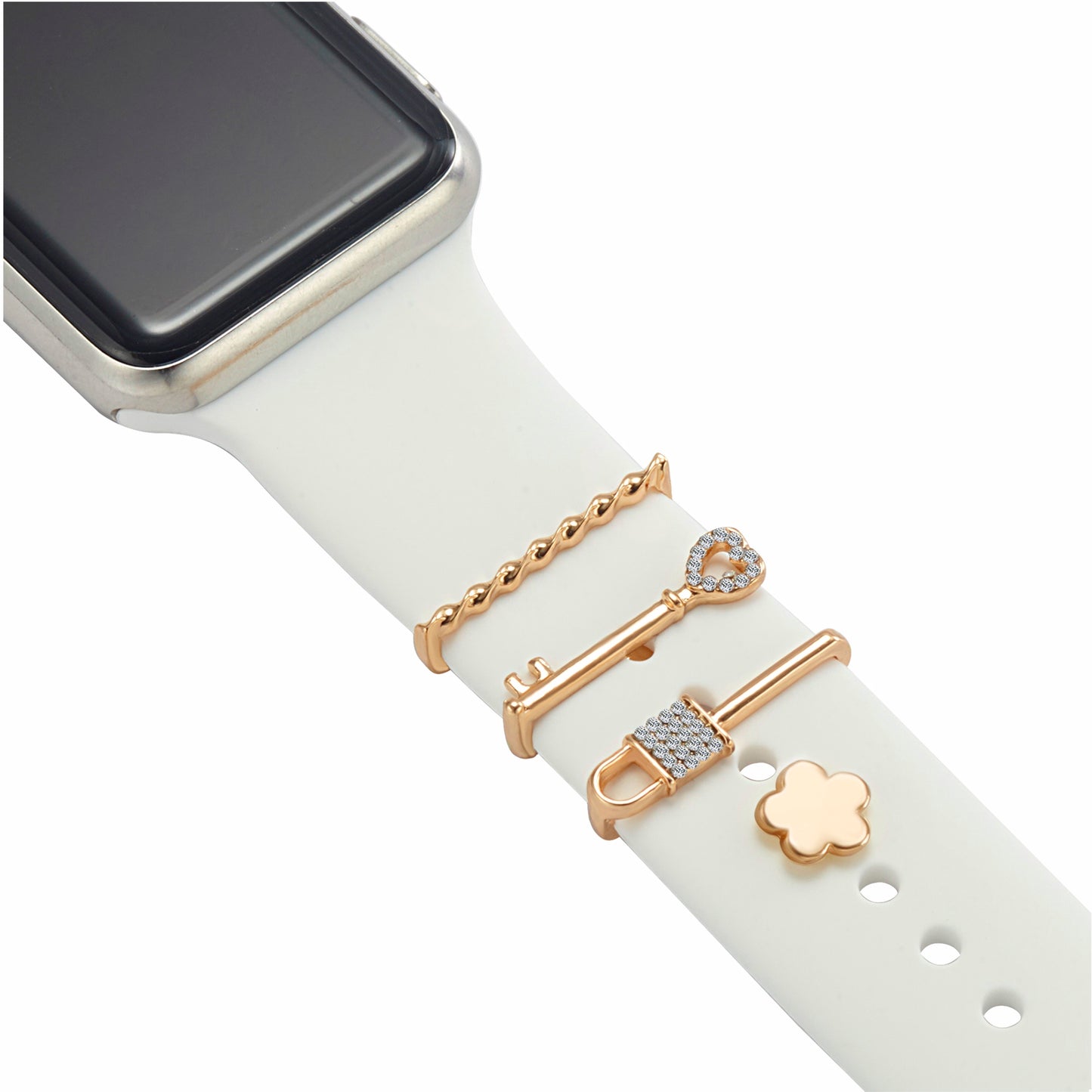 Ein weißes Arktisband-Smartwatch-Armband, individuell anpassbar mit vier goldenen Arktisband-Apple-Watch-Armband-Anhängern – einem gedrehten Stab, einem Schmucksteinschlüssel, einem Schmucksteinschloss und einer kleinen Blume. Das silberne Arktisband-Gehäuse ist oben links teilweise zu sehen.