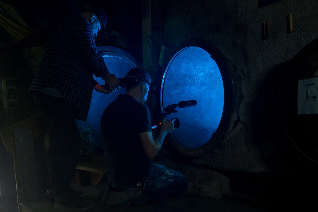 Rainer Wolf filmt eine Szene in einem dunklen Tunnel im Bergwerk, der mit blauem Licht erhellt wird.