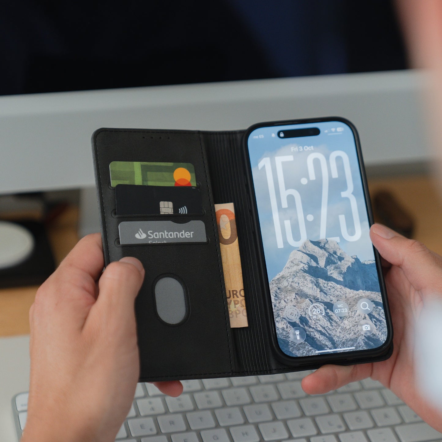 Jemand hält ein geöffnetes arktis iPhone 17 Pro Book Case mit Karten, Bargeld und einem Smartphone, das einen Berg-Sperrbildschirm zeigt.