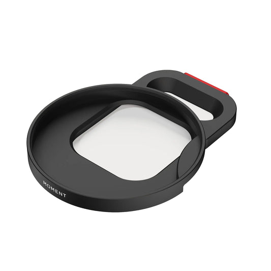 Der MOMENT 67mm QuickLock Filter Mount für iPhone 17 Pro ist ein schwarzer, rechteckiger Telefonobjektivadapter mit einem runden Rand, der auf einem weißen Hintergrund abgebildet ist.