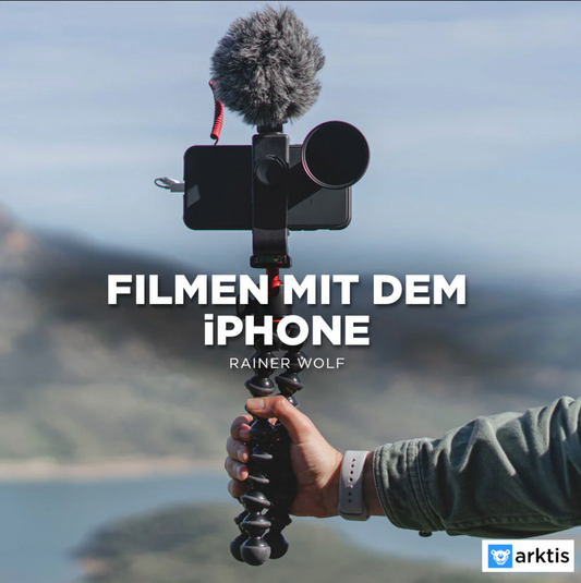Eine Person hält ein iPhone mit externem Mikrofon auf einem Stativ. Der Text lautet „Filmen mit dem iPhone – Rainer Wolf“. Im unscharfen Landschaftshintergrund ist „professionell filmen mit der iPhone Academy von arktis.de – Grundlagen Filmen mit dem iPhone“ hervorgehoben.