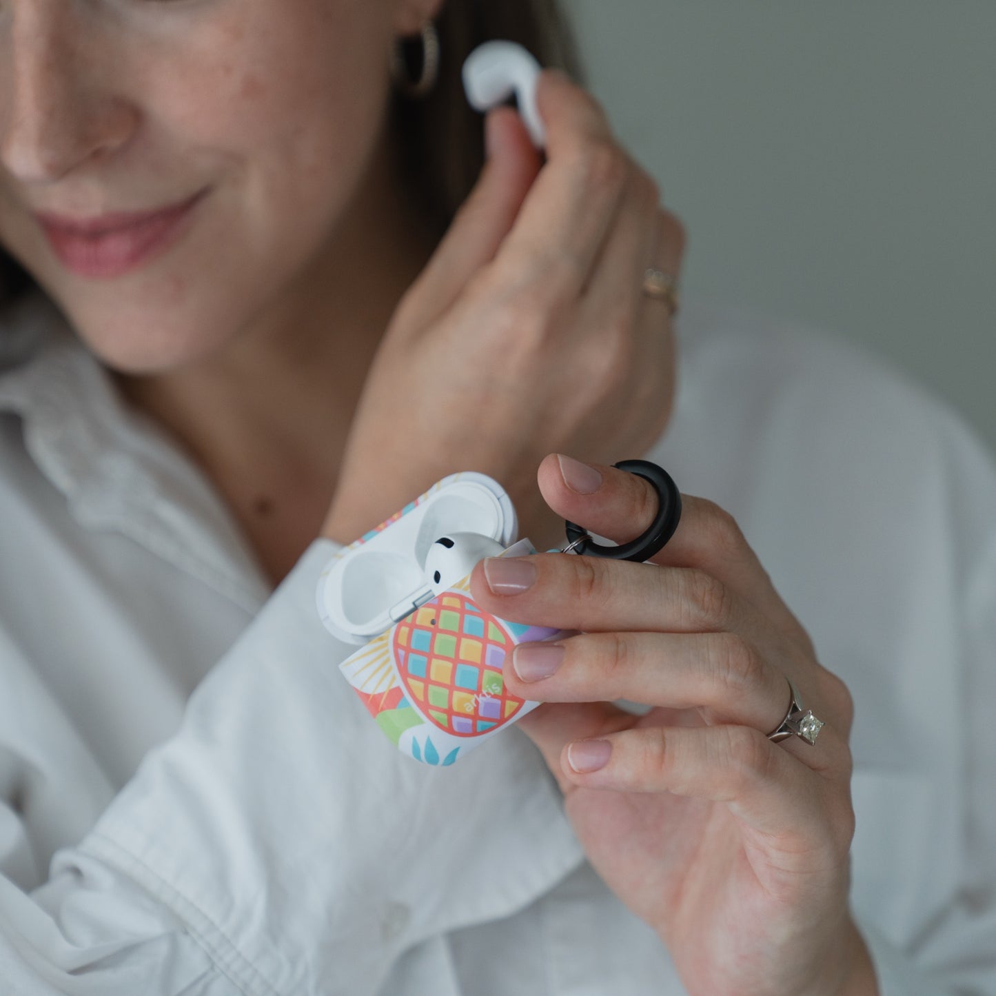 Eine Person, die ein geöffnetes AirPods-Etui in der Hand hält, auf dem eine Arktis AirPods 5 Hülle – Tropic Pineapple sitzt.