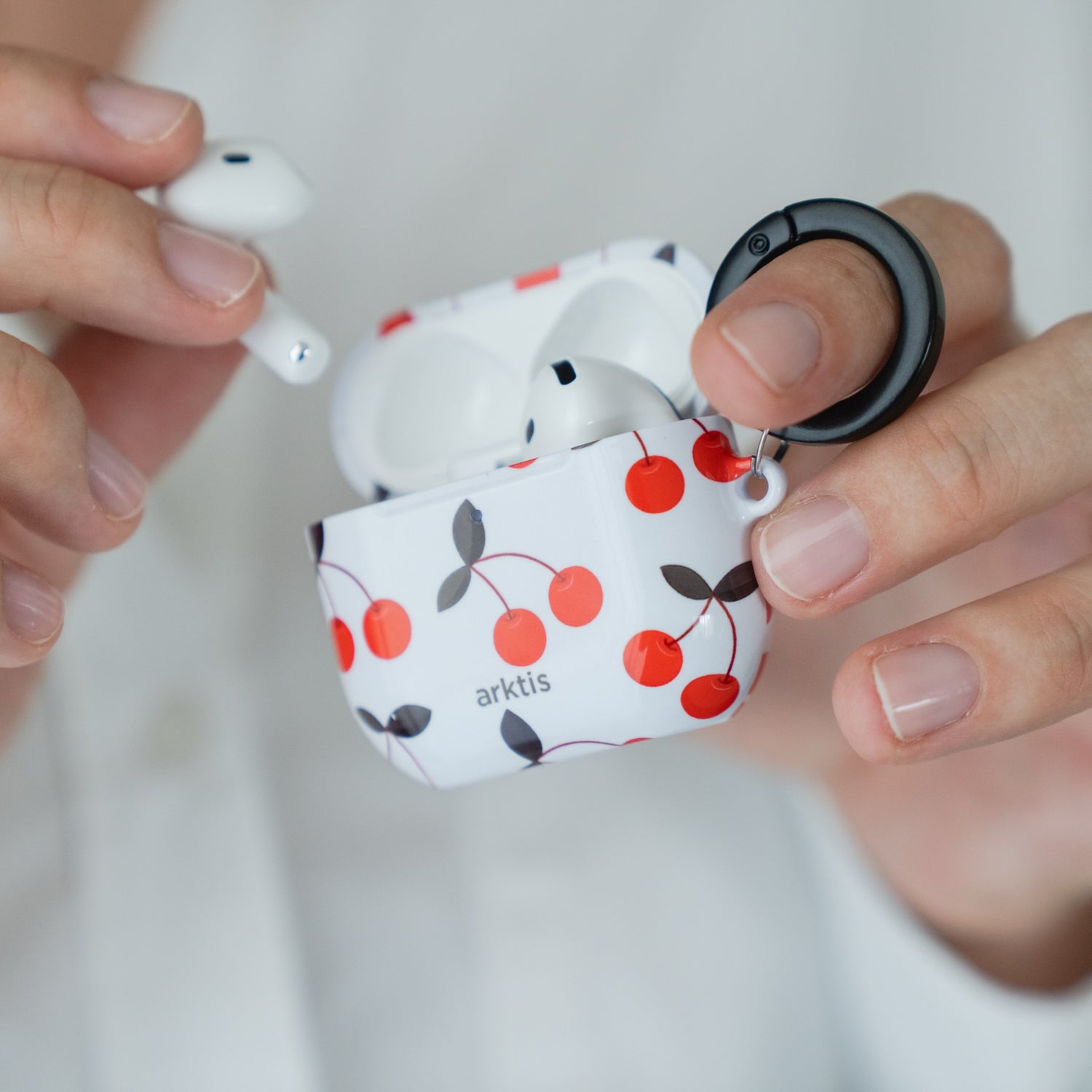 Jemand hält eine Arktis AirPods 5-Hülle in der Farbe Cherry in der Hand und nimmt mit der anderen Hand einen Ohrhörer heraus.