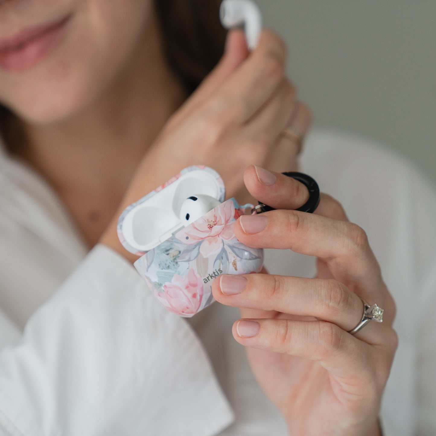 Eine Person hält eine geöffnete Arktis AirPods 5 Hülle – Pastel Flowers mit Blumenmuster in der Hand.