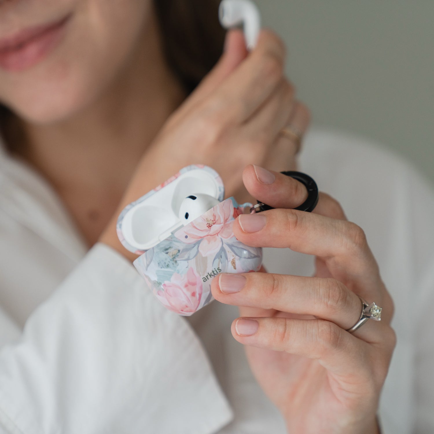 Eine Person hält eine geöffnete Arktis AirPods 5 Hülle – Pastel Flowers mit Blumenmuster in der Hand.
