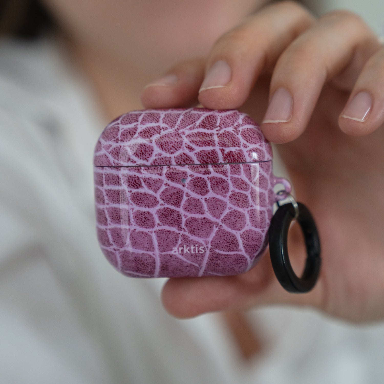 Eine Hand, die eine Arktis AirPods 5-Hülle – Pink Lizard-Hülle mit schwarzem Ringaufsatz – hält.