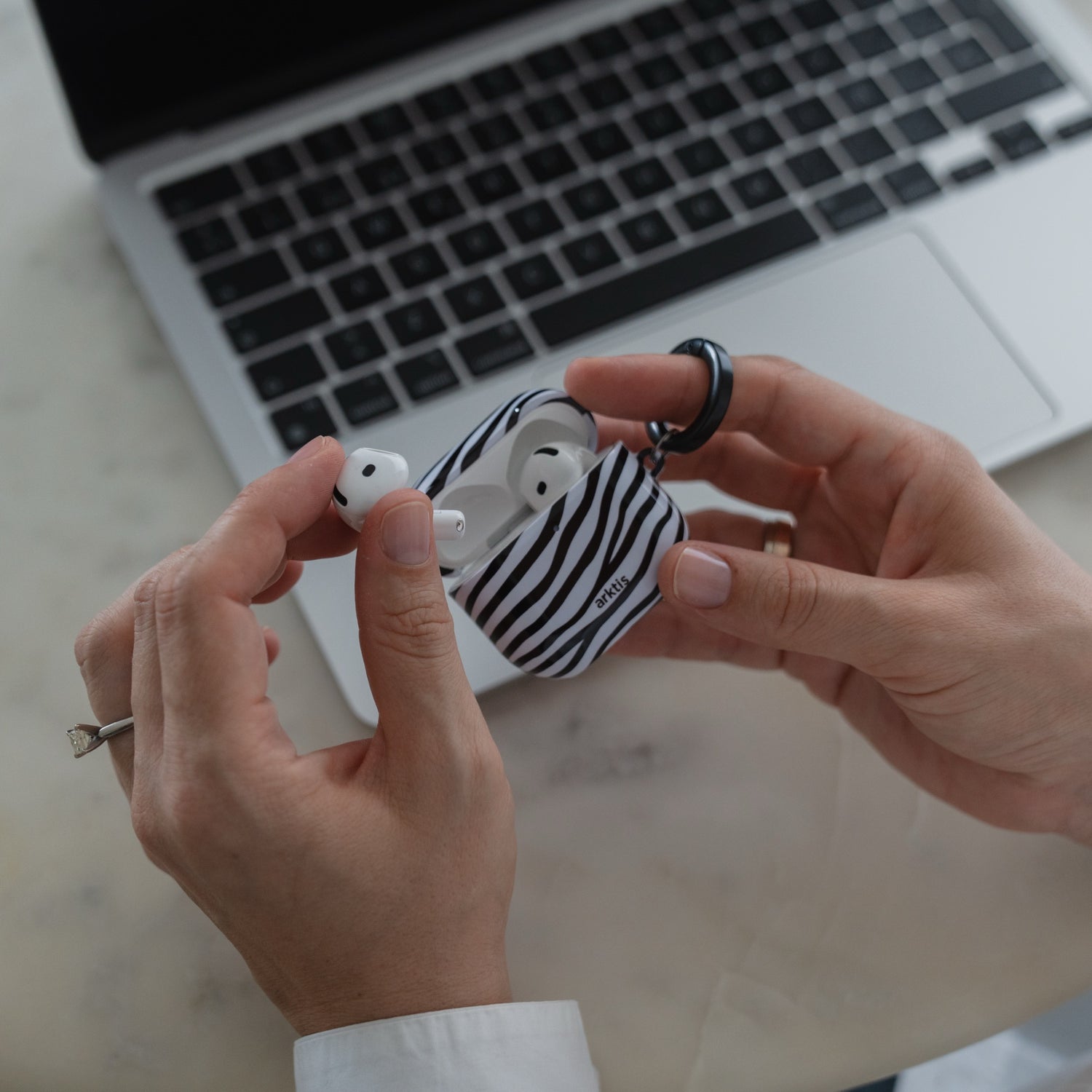 Hände, die eine Arktis AirPods 5 Hülle – Zebra-Schutzhülle für kabellose Ohrhörer halten.