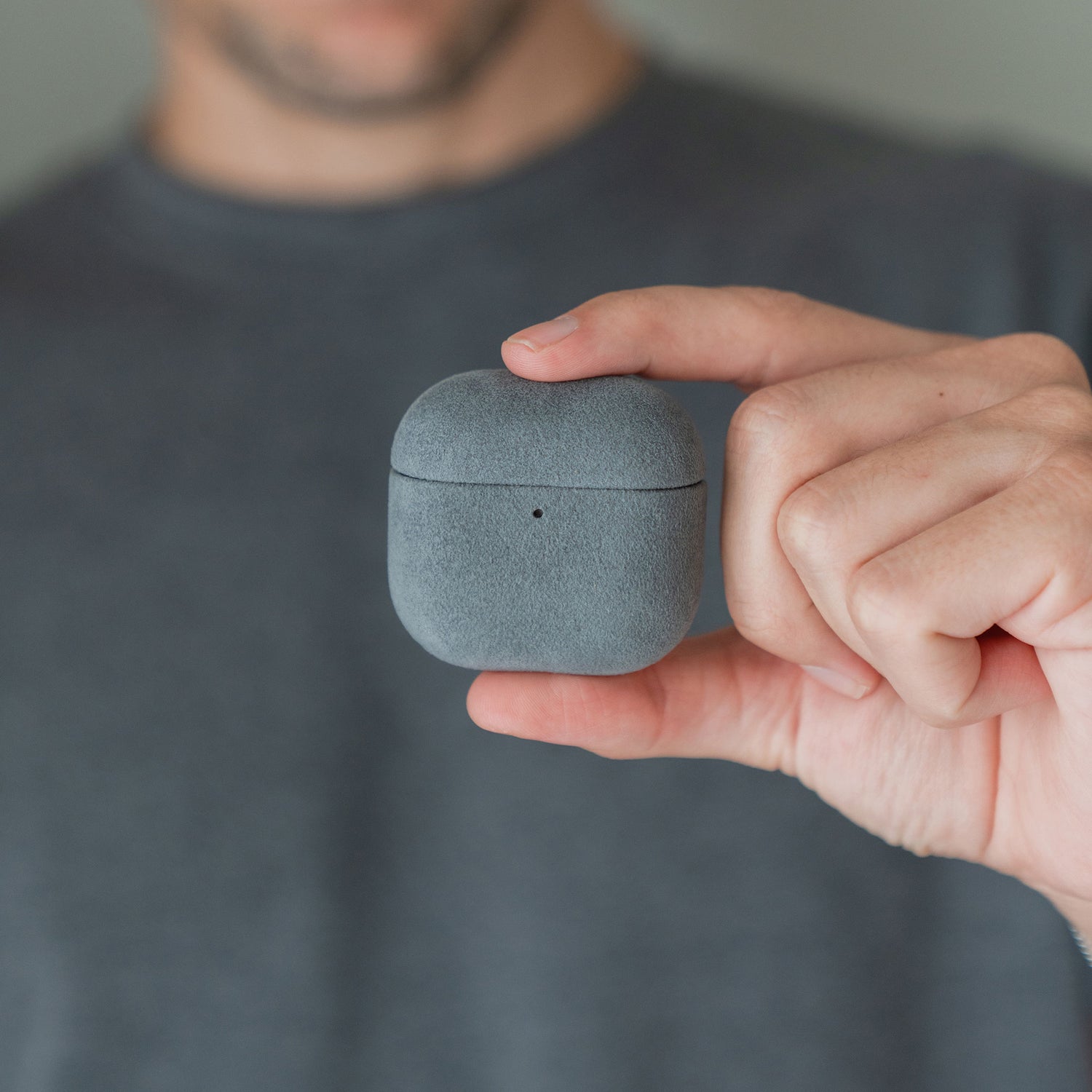 Jemand hält eine Arktis AirPods Pro 3-Hülle aus Alcantara zwischen Daumen und Zeigefinger.