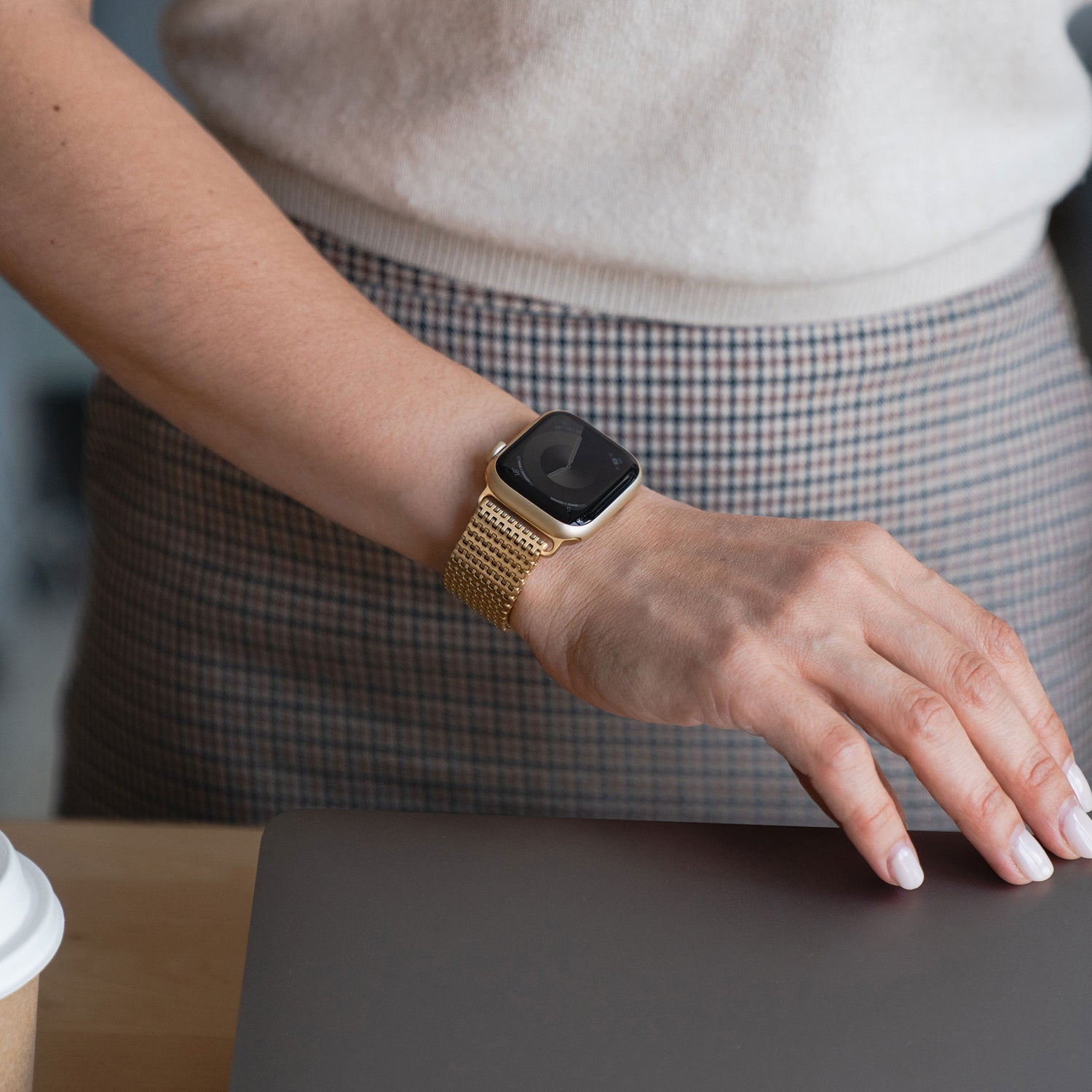 Jemand, der das Arktisband Apple Watch Edelstahlarmband „Aurora“ trägt, legt seine Hand auf einen Laptop neben einer Kaffeetasse.