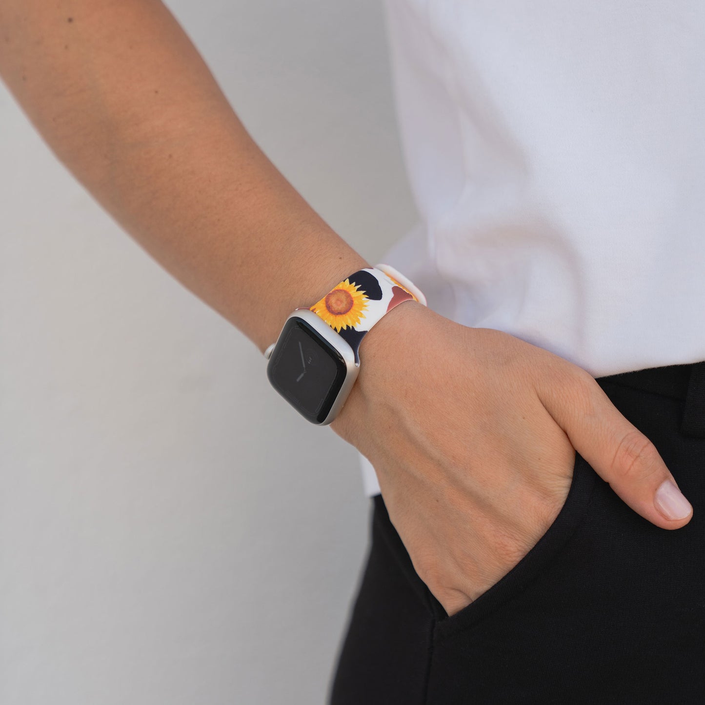 Eine Person, die ein arktisband Sunflower Apple Watch Armband und ein weißes Hemd trägt und die Hand in der Tasche einer schwarzen Hose hat.