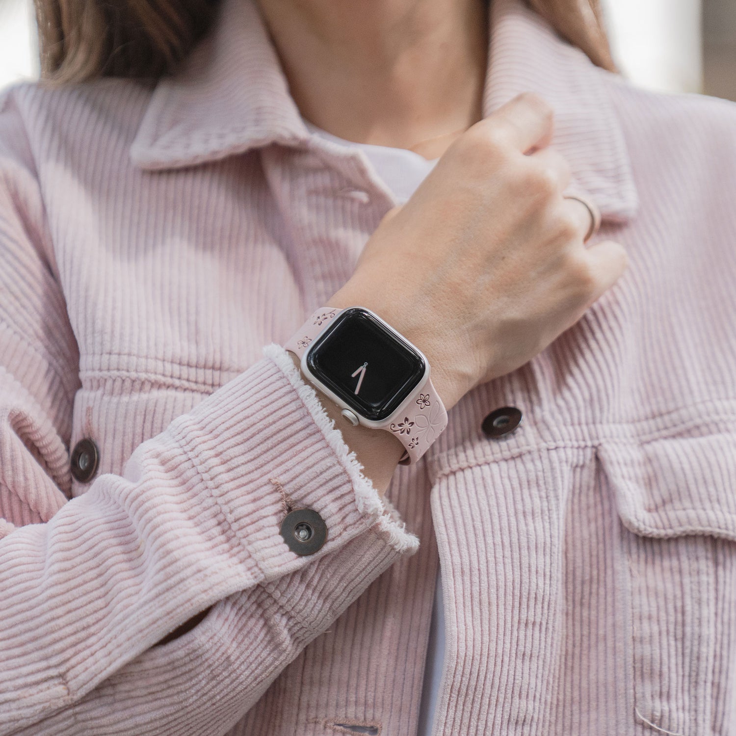 Eine Person trägt ein rosafarbenes Arktisband Apple Watch Silikonarmband "Bloom" mit Blumenmuster, kompatibel mit Apple Watch, das die Uhrzeit 1 auf dem Display anzeigt.