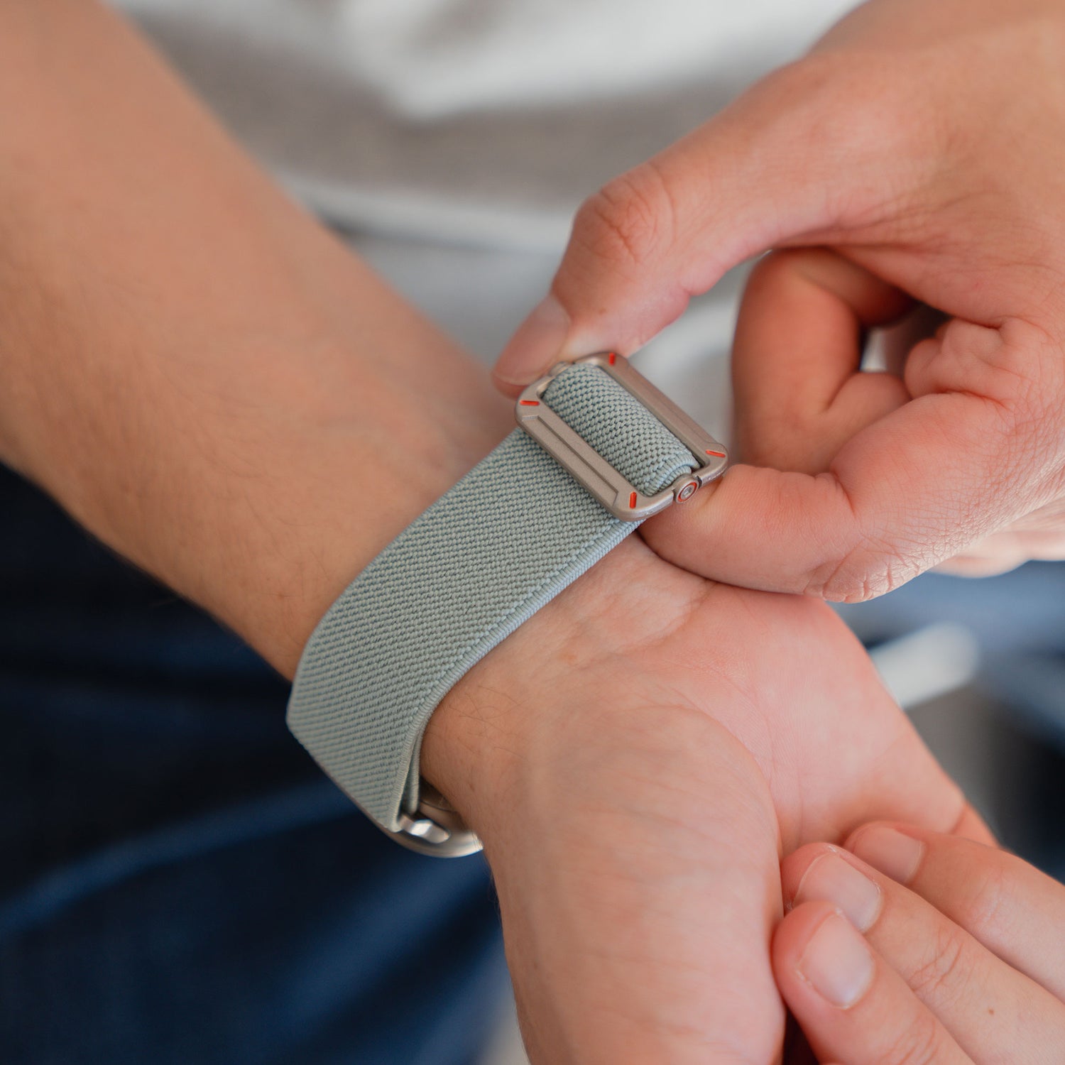 Das arktisband Apple Watch Nylonarmband "FlexOne" in grau wird von einer Person am Handgelenk befestigt und sorgt so für einen sicheren und bequemen Sitz.