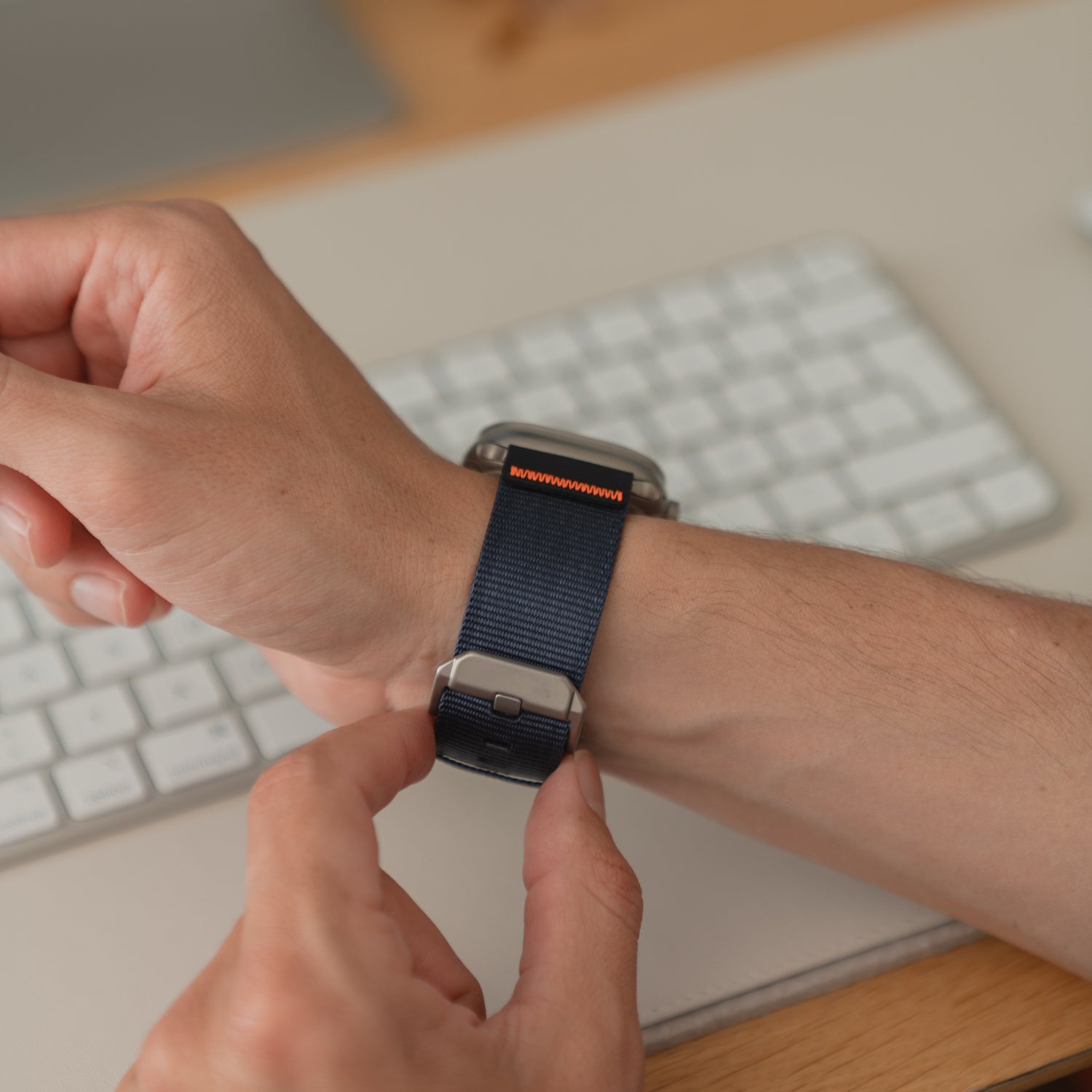 Nahaufnahme einer Person, die ein arktisband Apple Watch Armband "Terra" mit extra breitem 24-mm-Nylonband an ihrem Handgelenk in der Nähe einer Computertastatur befestigt.