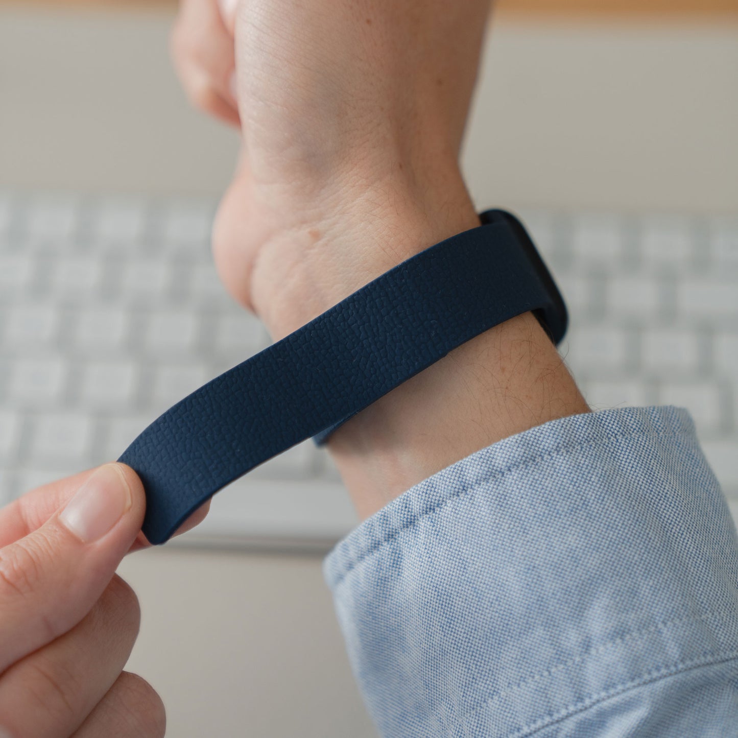 Eine Person trägt das arktisband Apple Watch magnetisches Silikonarmband "Flexy" von arktisband am Handgelenk nahe einer Computertastatur.