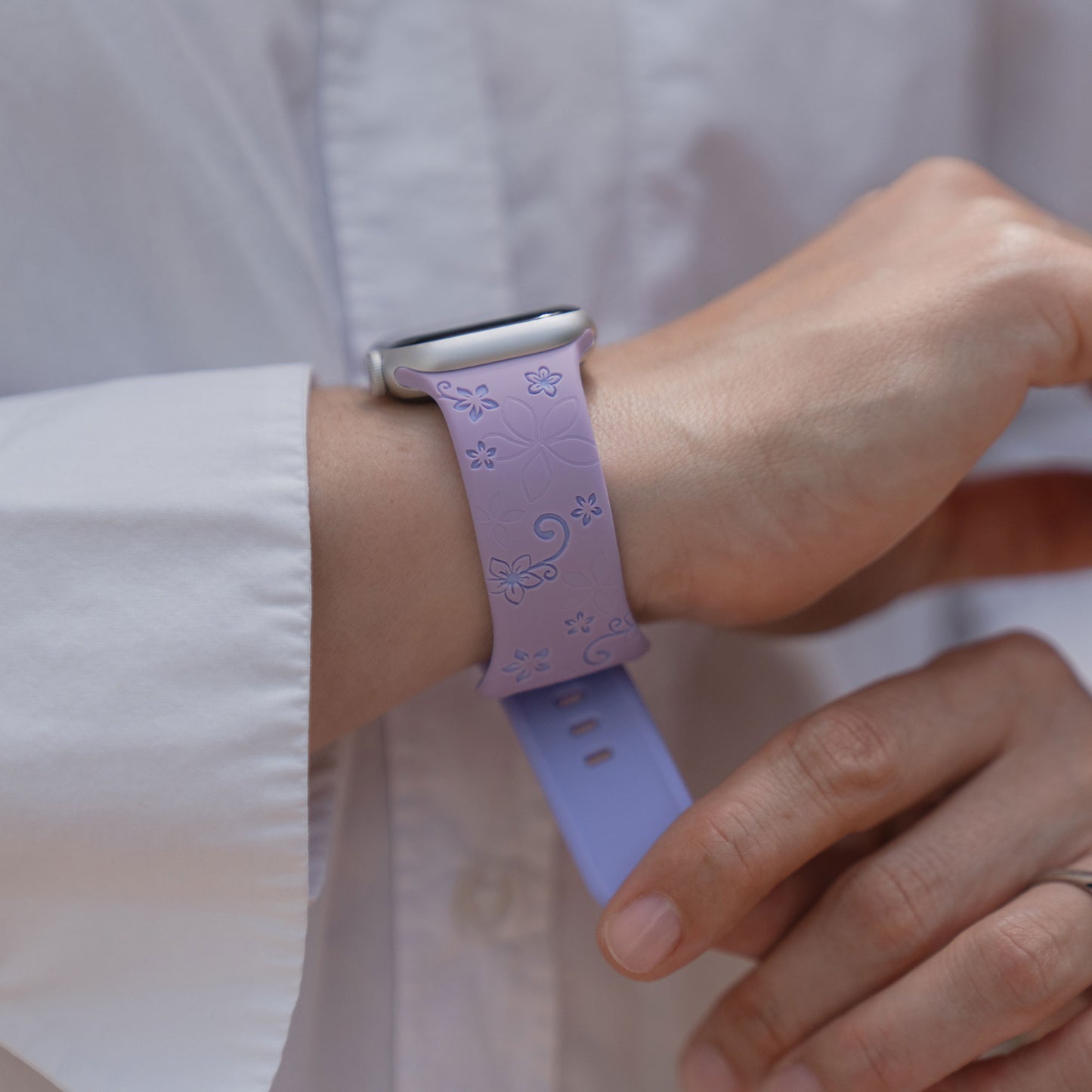 Eine Person trägt das arktisband Apple Watch Silikonarmband "Bloom" mit einem floralen Design am Handgelenk, gepaart mit einem weißen Hemd.